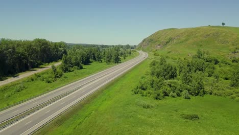 Aerial-Low-level-flying-over-highway-in-the-highlands-View-of-the-forest-passing-cars-trucks