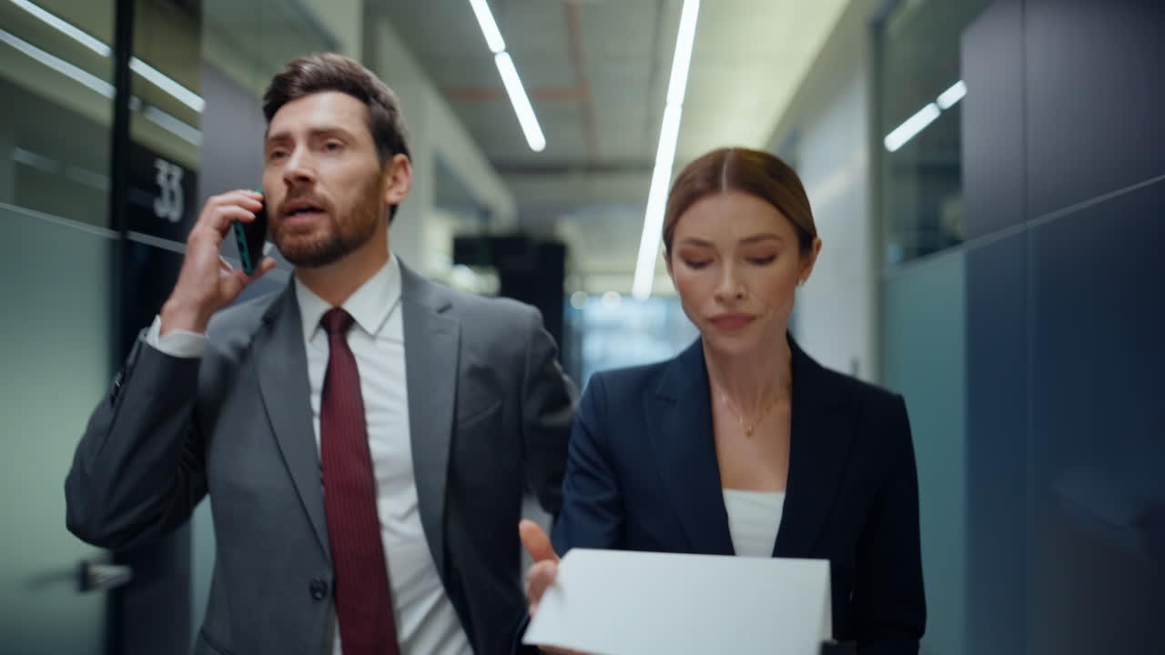 Confident boss talking mobile phone walking vestibule with secretary closeup