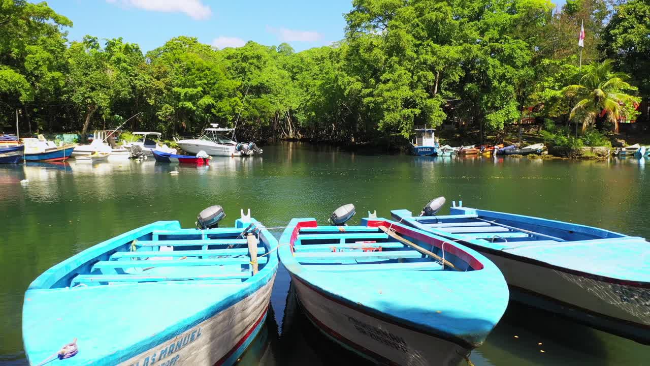 espectacular sobrevuelo bajo de lanchas de motor turquesa amarradas y atadas juntas por una aldea portuaria protegida junto al mar tropical, nagua, república dominicana, enfoque aéreo superior