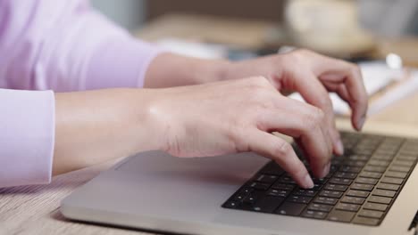 mano de cerca de una mujer de negocios escribiendo teclado computadora portátil en la oficina de escritorio