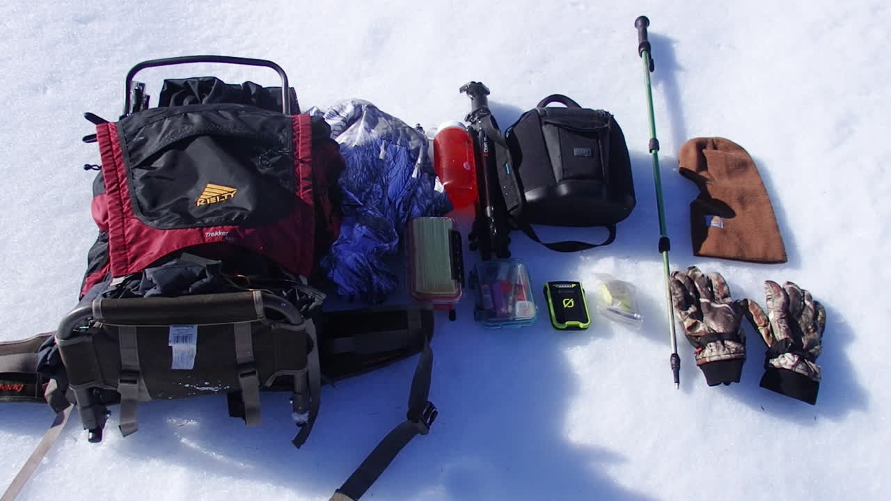 Nature and wildlife photography and outdoor gear from a backpack on display in the snow during a winter on Kodiak Island Alaska