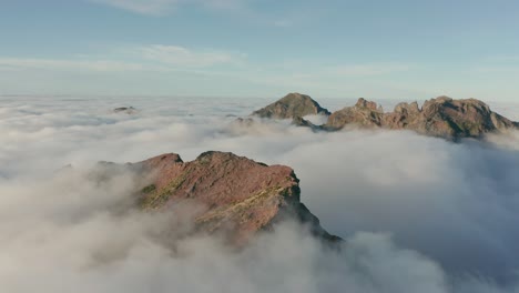 majestic mountain peaks of madeira above white fluffy clouds with sunshine