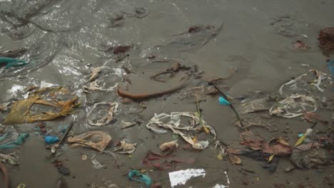 una toma cinematográfica de residuos plásticos enterrados en la arena de esta playa en la india