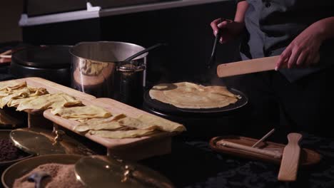 chef cooking fresh crepes on a hot griddle at a wedding dessert table