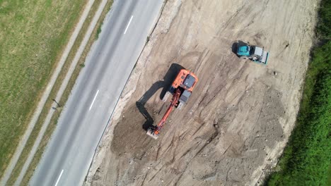 Aerial-Overhead-View-Of-Excavator-Levelling-Ground-In-Preparation-For-New-Road-In-Switzerland