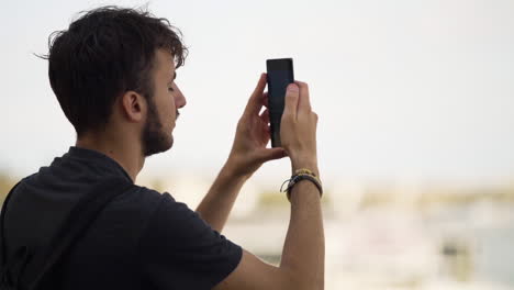 Man-walking-into-bright-frame-to-take-photo-of-city-in-blurred-background