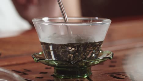 agregar agua caliente en un tazón de vidrio auténtico con hojas de té verde chino