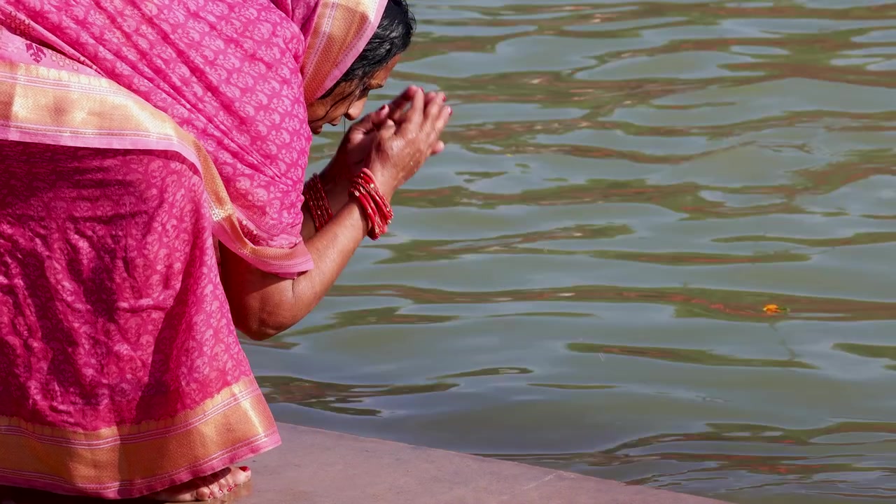 Donna indù che offre preghiere presso un fiume sacro durante un tradizionale rituale religioso