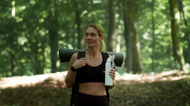 Woman with Yoga Mat and Water Bottle in Forest
