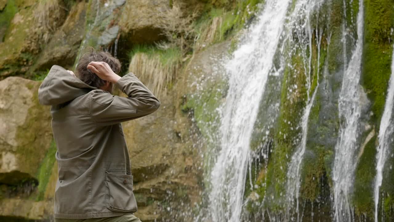 senderismo en un día nublado - un joven excursionista se detiene para admirar las cascadas y se quita la capucha - la ruta de las siete piscinas - cataluña españa - ruta dels set gorgs de campdevànol
