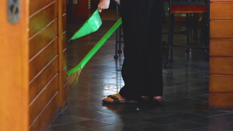 person sweeping floor with broom and dustpan