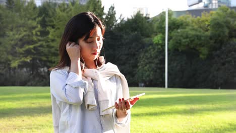 아름다운 아시아 여성이 중국 상하이의 공원에서 빛 아래에서 음악을 듣고 있습니다.