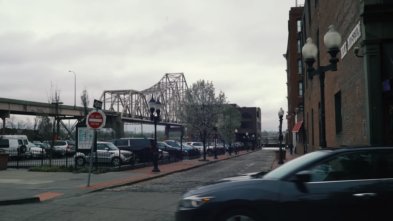 A bridge and street in St. Louis, MO with a parking lot in foreground. Dark clouds and overcast skies.