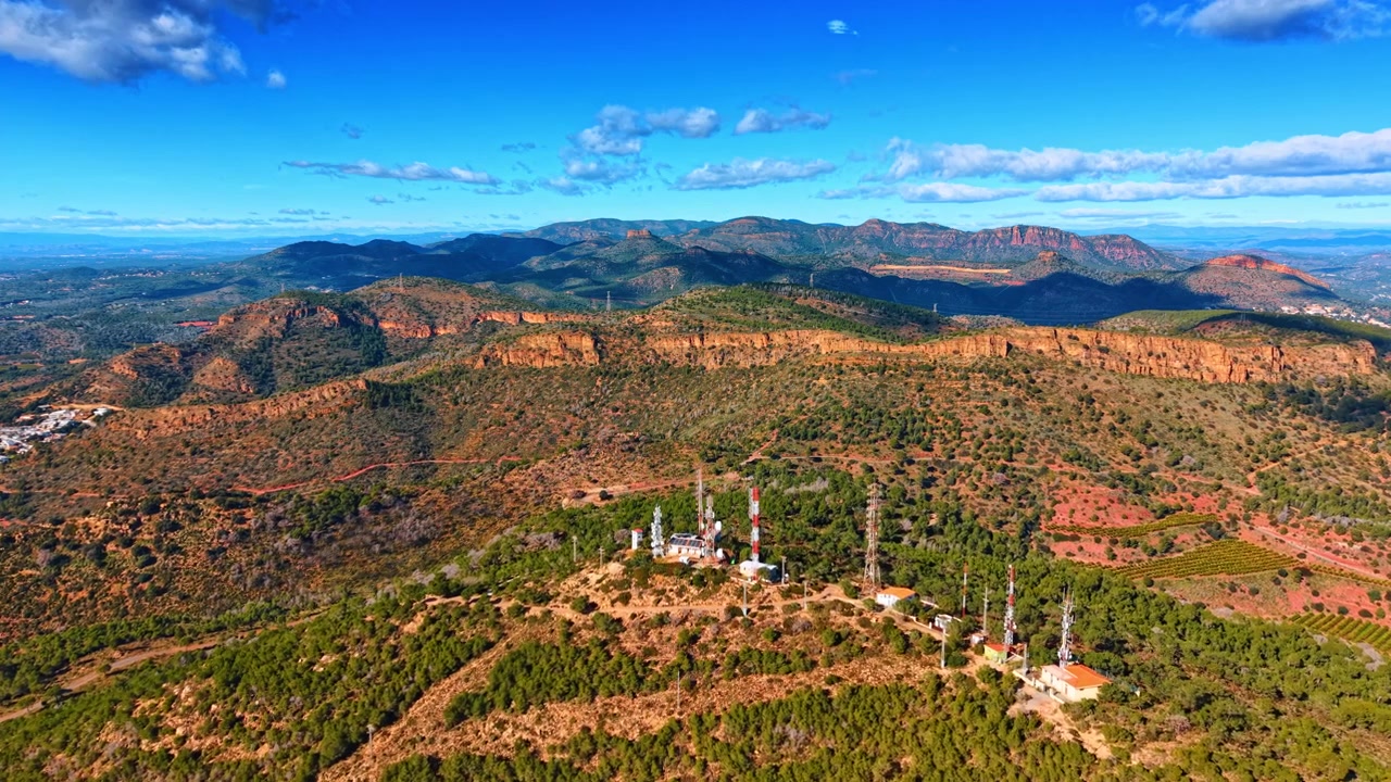 Veduta panoramica aerea di colline verdi e torri di telecomunicazione. Ampia veduta aerea di un lussureggiante paesaggio montano verde con antenne di telecomunicazione in cima sotto un cielo blu.