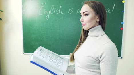 beautiful girl with a book near the blackboard at school