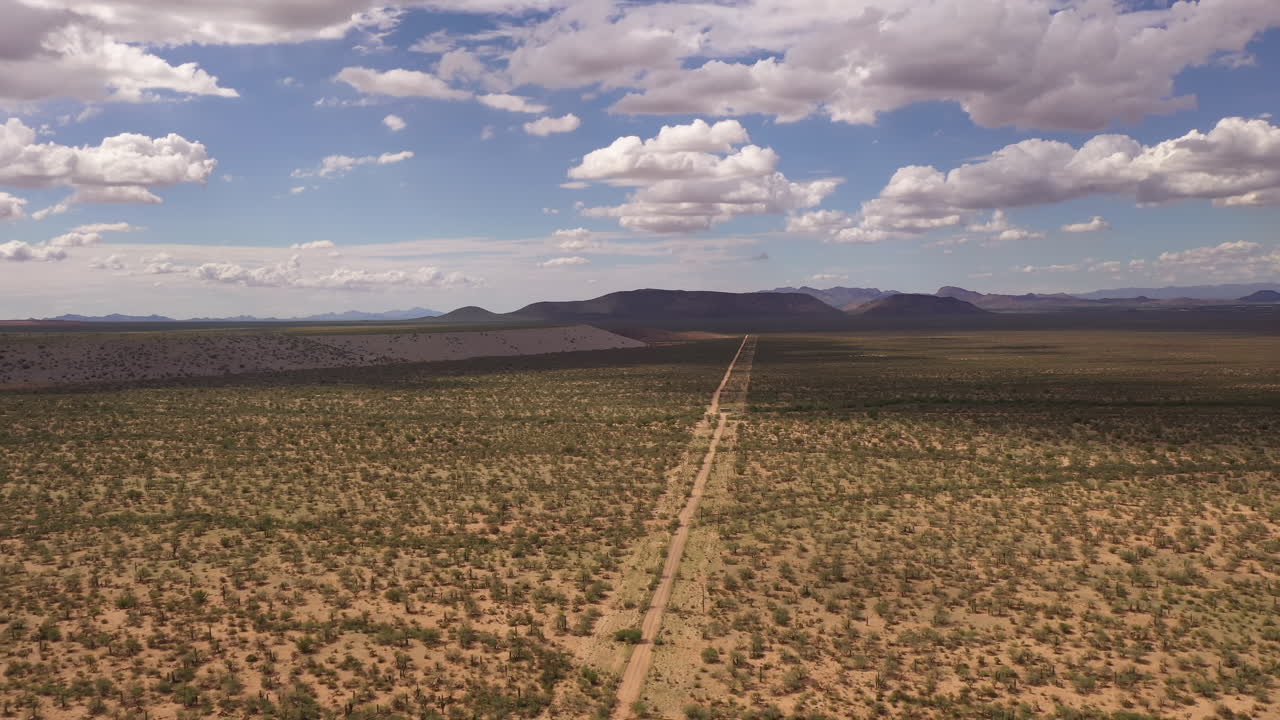 camino que conduce a la distancia en el vasto paisaje del sur de arizona, drone hacia atrás