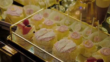 Close-up-shot-showing-a-varied-range-of-cakes-based-on-vanilla-cream-with-strawberries,-lollipops,-cupcakes-and-tiramisu