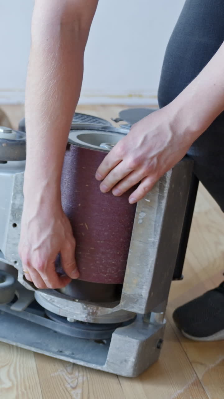 Vertical close-up of sandpaper being changed on a floor sander used for pine wood floors.
