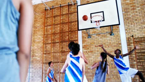 school students playing basketball in basketball court