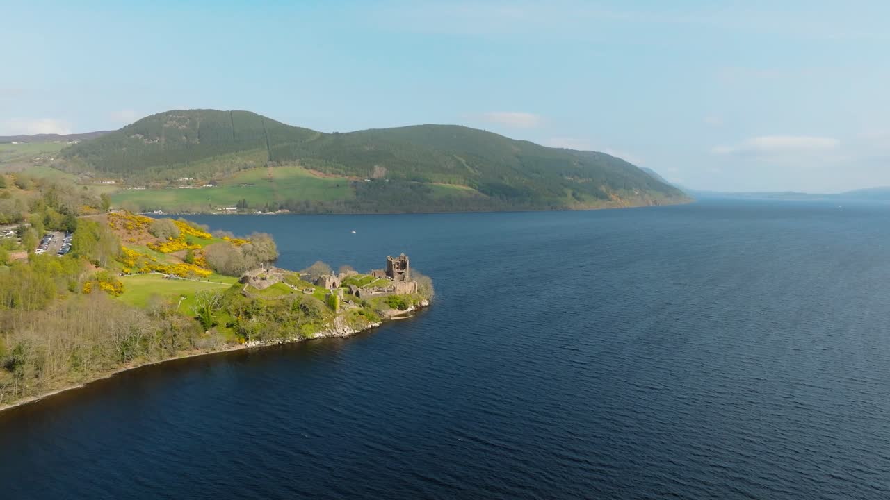 Aerial drone footage of Urquhart Castle on the shores of Loch Ness, Scotland. Sweeping views of the historic ruins, the famous loch, and the surrounding dramatic Highland landscape