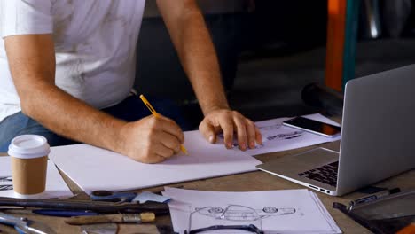 Male mechanic having coffee while working on table 4k