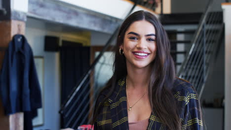 retrato de una mujer sonriente dueña de una tienda de moda de pie frente a una exhibición de ropa