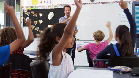 niños de la escuela levantando las manos en una clase de escuela primaria