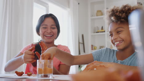 Two-laughing-pre-teen-girls-having-fun-playing-with-modelling-clay-at-home,-close-up,-low-angle