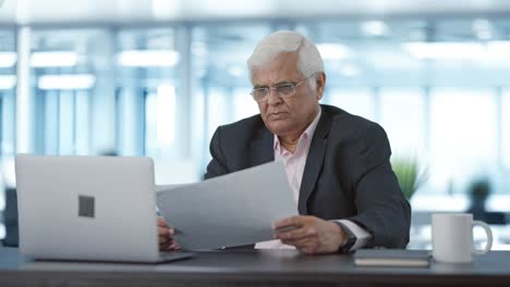 serious indian senior manager reading business reports