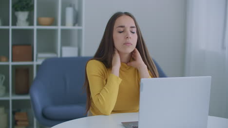 tired woman suffering from neck pain working till on laptop. a woman has a sore neck after hard work at a table with a laptop. pain in the neck.