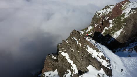 una mujer está sentada sola en lo alto de un acantilado en la montaña pico ruivo en madeira