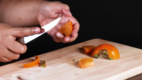 hands skillfully cutting a ripe persimmon