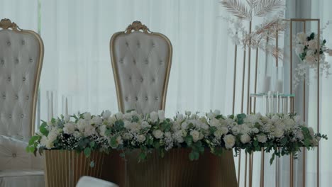 luxurious wedding reception table adorned with a lush floral garland and elegant high-back chairs