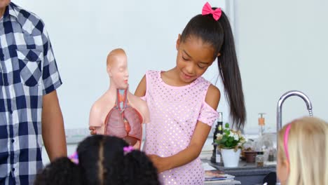 Front-view-of-Asian-schoolgirl-explaining-human-skeleton-model-in-the-classroom-4k