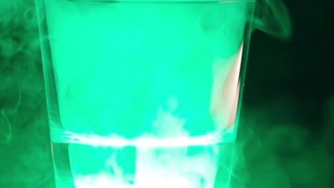 Close-up-of-a-green-smoke-flying-inside-a-glass-or-glass-container