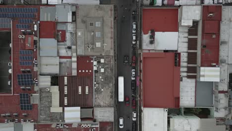 Straight-down-aerial-of-vehicles-on-narrow-street-in-Oaxaca,-Mexico