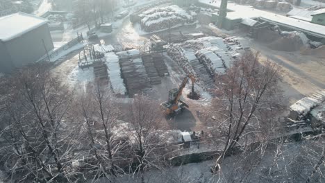 aerial view of sawmill and cranes loading tree logs in winter season