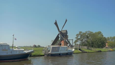 dutch old windmill on a dike near the water, a small dolly shot in slowmotion