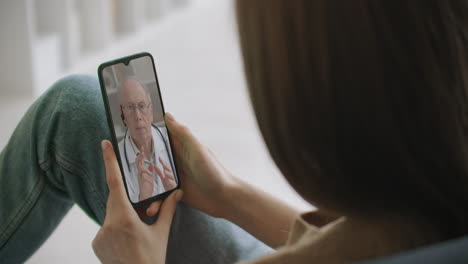 Die-Medizinische-Assistentin-Trägt-Ein-Weißes-Kittel-Headset-Und-Ruft-Einen-Entfernten-Patienten-Auf-Dem-Smartphone-An.-Arzt-Spricht-Mit-Dem-Kunden-über-Die-Virtuelle-Chat-Telefon-App.-Telemedizinische-Ferngesundheitsdienste