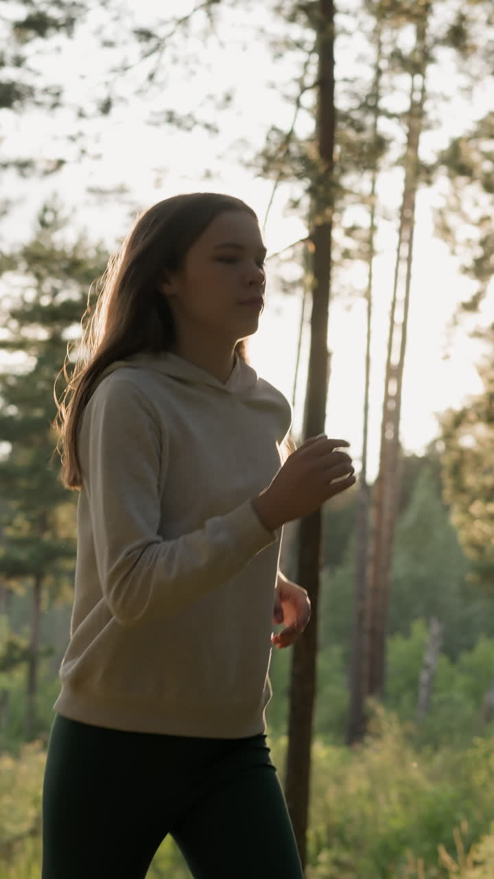 atleta mujer corre en el bosque al atardecer. joven lleva a cabo rutina de cardio para mejorar el bienestar general por la noche. mantener la salud física