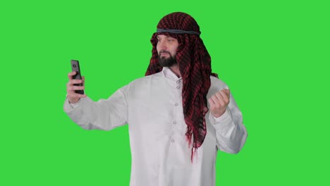 arabian man walking and making a selfie with his phone on a green screen, chroma key