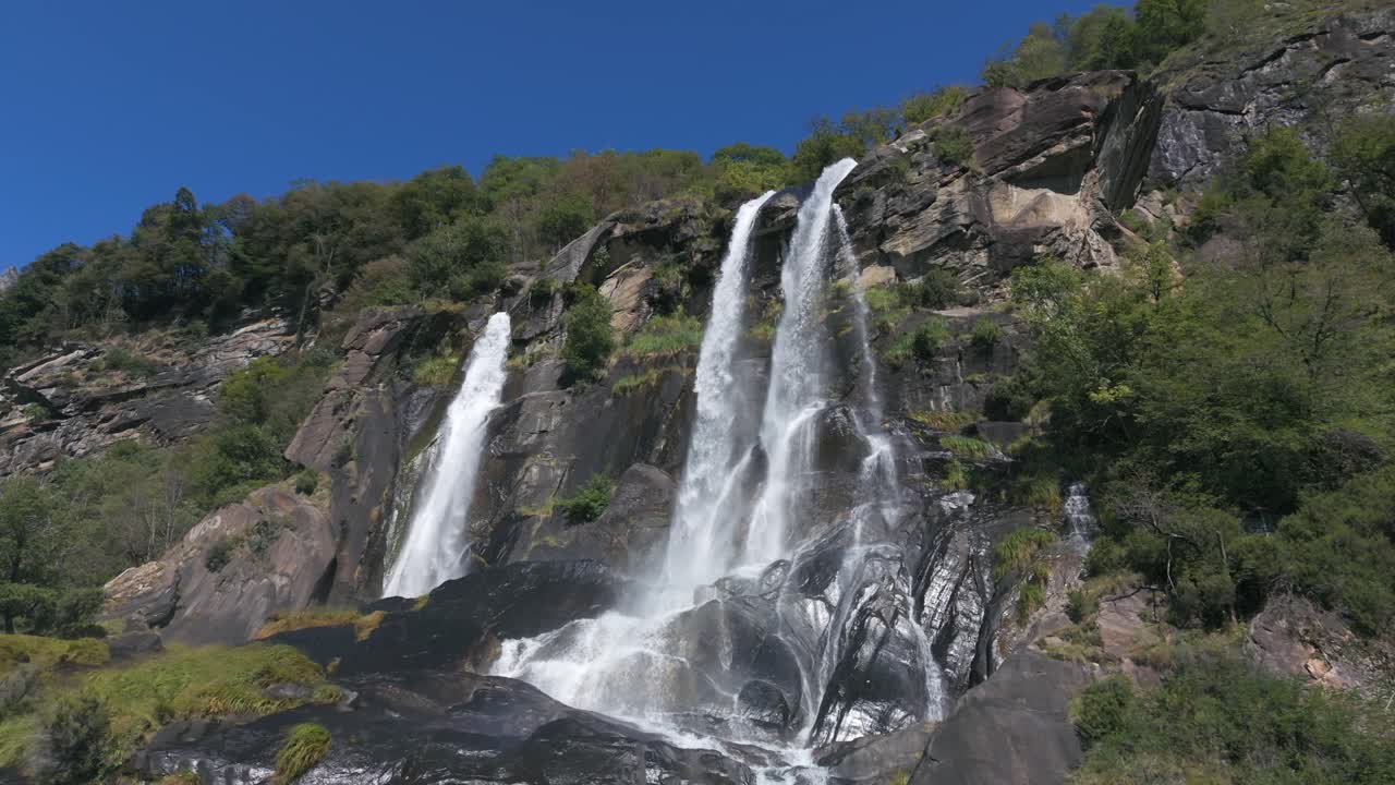 Machtige Acquafraggia-watervallen die van rotsen naar beneden stromen in de Italiaanse Alpen. Zijdelings dronebeeld vanuit de lucht. Slowmotion