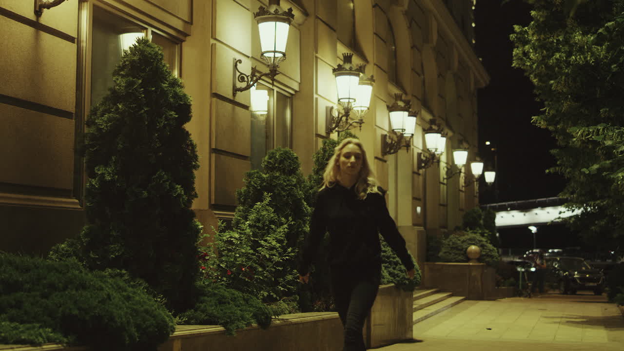 крутая девушка устраивает вечеринку в одиночку на ночной улице у городских огней в городской зоне.