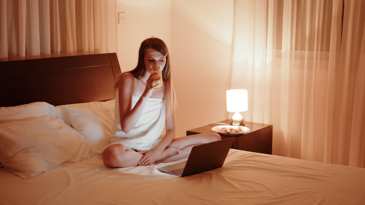 노트북과 주스로 침대에서 휴식을 취하는 여자