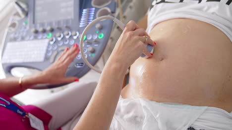 doctor doing sonogram scan to a pregnant woman. obstetrician moving transducer on the belly of the future mother. modern medical equipment for ultrasound. close-up.