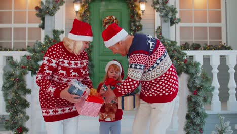 mature grandparents family with granddaughter exhcanging gifts boxes presents for christmas at home