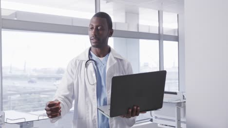 African-american-male-doctor-using-laptop-in-hospital-room,-slow-motion