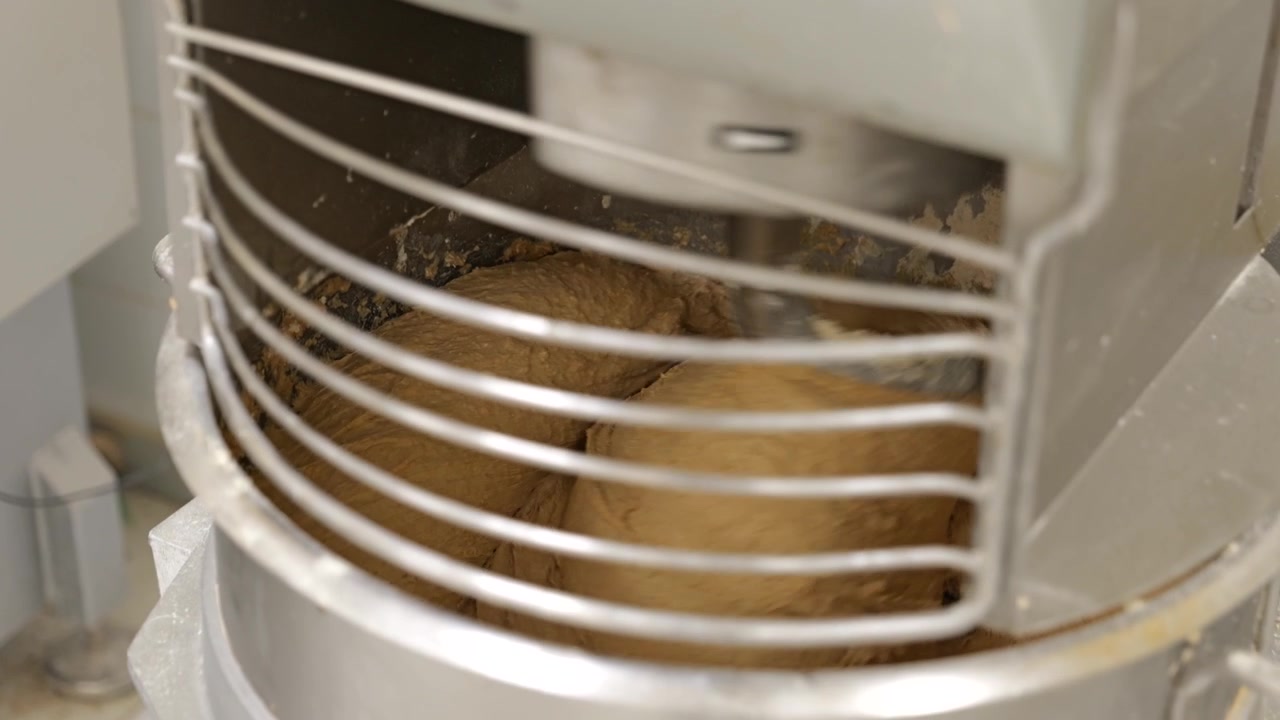 Primo piano ravvicinatissimo di impasto per il pane che viene impastato all'interno di un'impastatrice a spirale.
