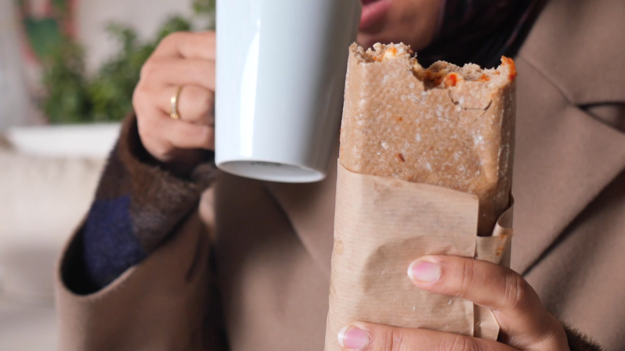 Close-up of Woman Eating a Wrap and Drinking Coffee
