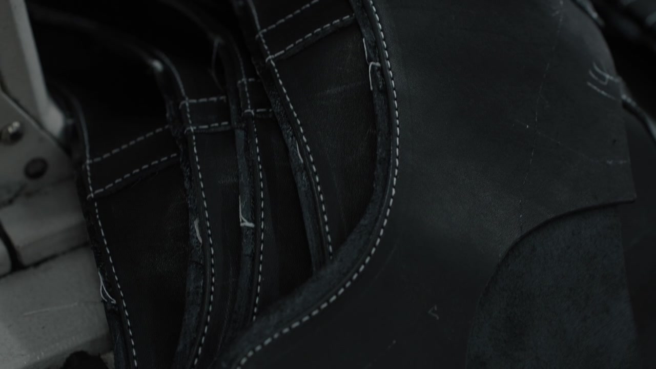 Empeines de zapatos de cuero negro apilados con costuras blancas en un taller